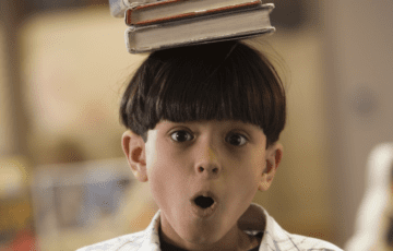 a boy balancing several books on his heads